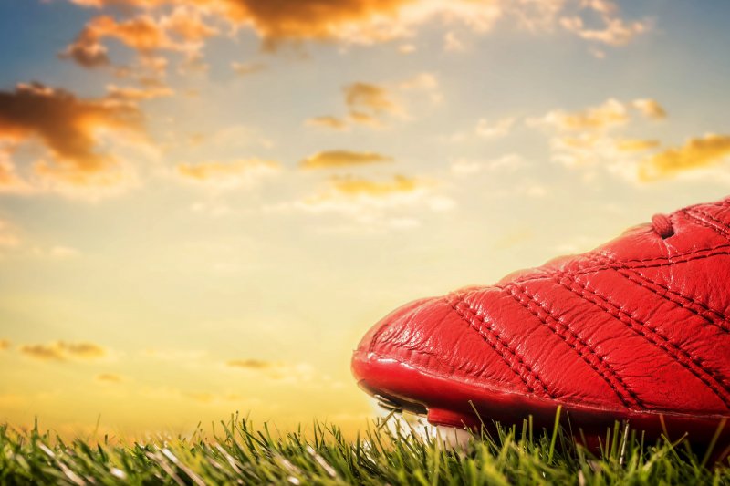 Football boot on pitch sunny backdrop Stock Image